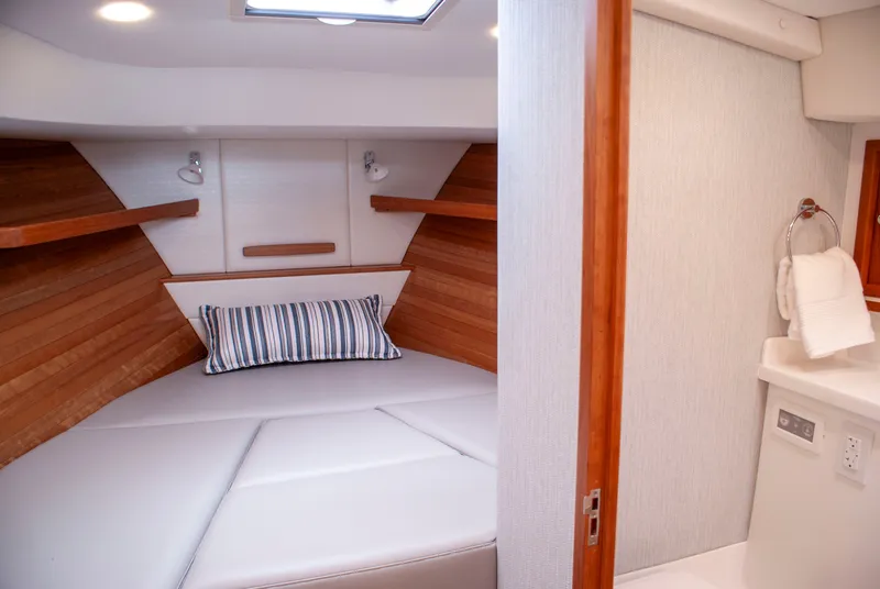 Slide: The Image of The 2027 MJM Yachts 38R cabin features a cozy bed with wooden walls and an adjacent bathroom. - 36