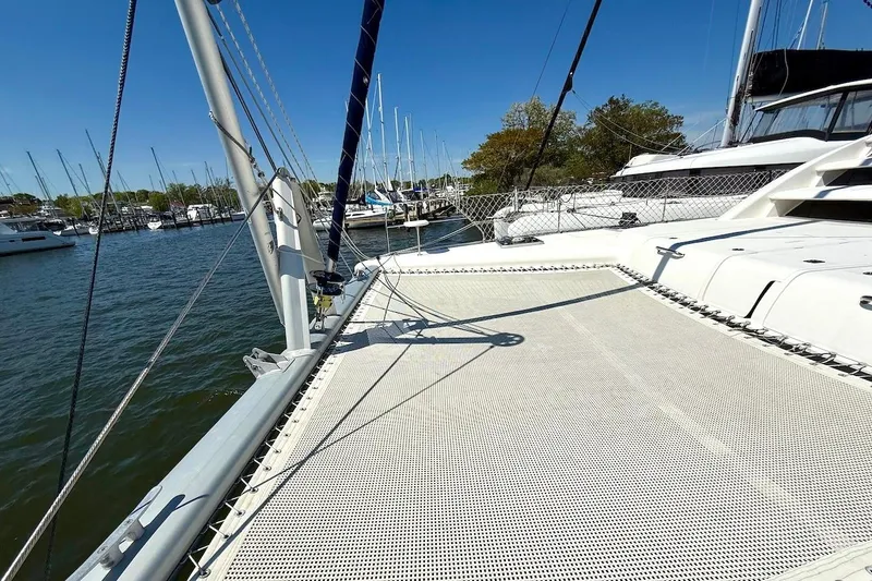 Slide: The Image of 2010 Leopard 46 catamaran docked at marina, featuring spacious deck and netting. - 10