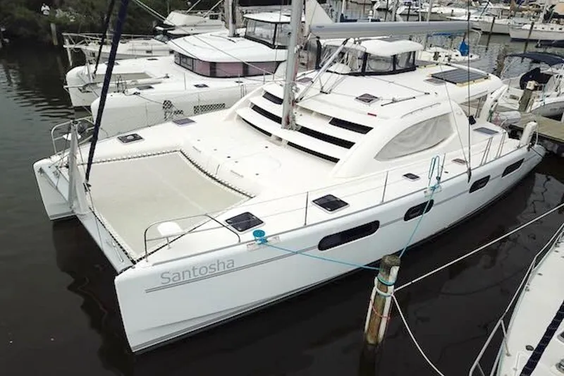 Slide: The Image of 2010 Leopard 46 catamaran docked at marina, named "Santosha," featuring spacious deck and sleek design. - 2