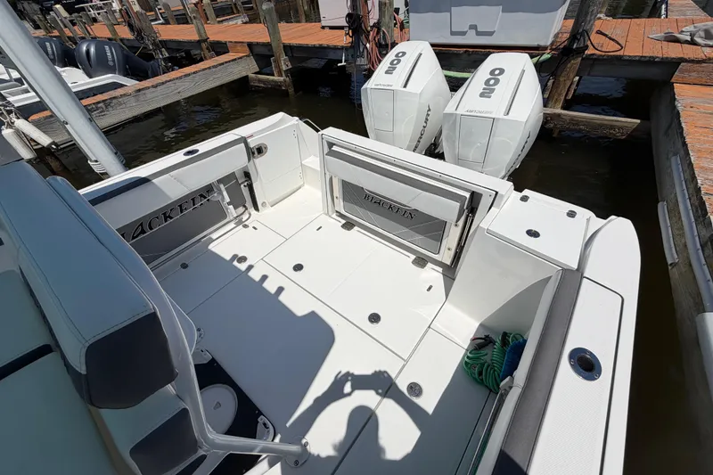 Slide: The Image of 2019 Blackfin 242 CC boat with dual Mercury engines docked at a marina. - 11
