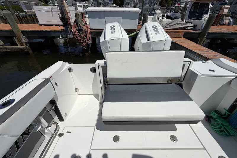 Slide: The Image of 2019 Blackfin 242 CC boat interior with seating and dual outboard engines at dock. - 15