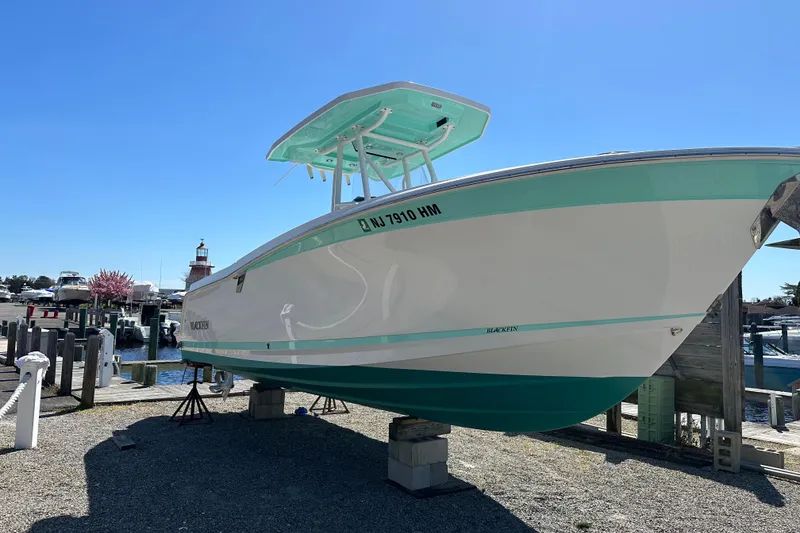 The Image of 2019 Blackfin 242 CC boat on stands, marina background, clear sky. - 2