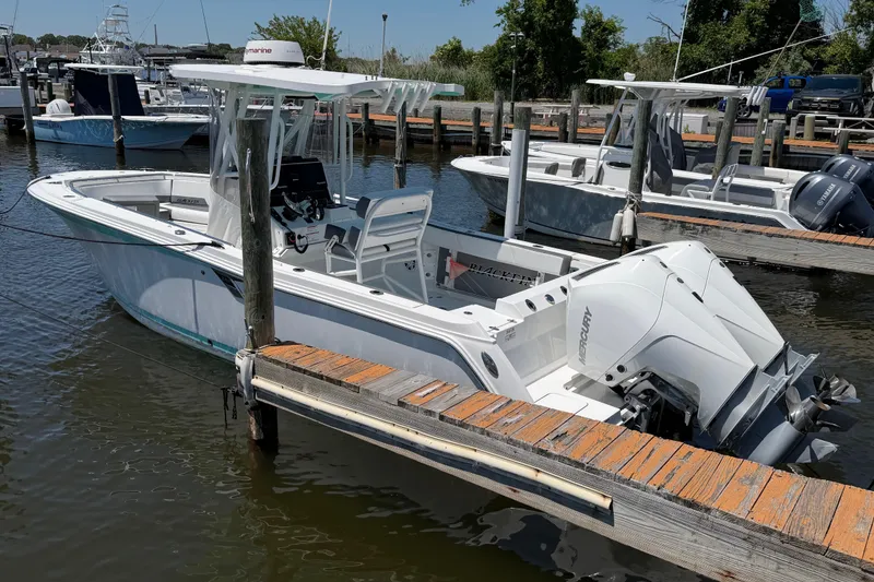 Slide: The Image of 2019 Blackfin 242 CC boat docked with twin Mercury engines in a marina setting. - 8