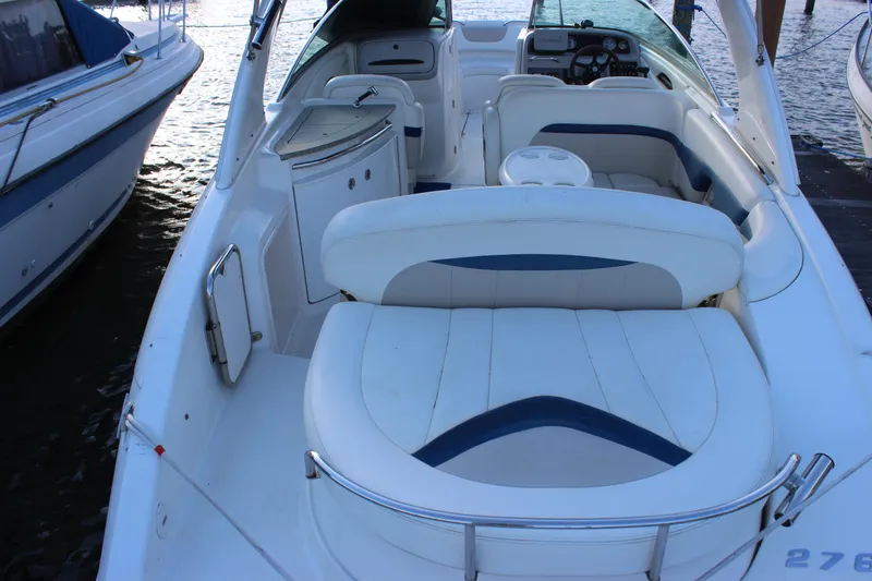 Slide: The Image of 2007 Chaparral 276 SSX boat interior with white seating and dashboard, docked by the water. - 8
