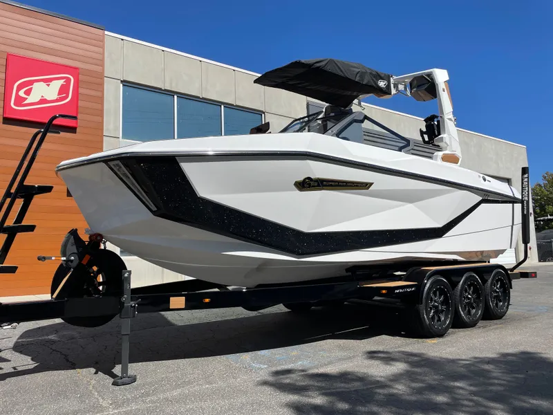 Slide: The Image of 2025 Nautique G23 boat on trailer in front of building. - 2