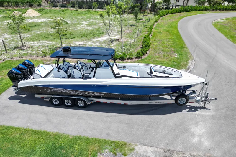 Slide: The Image of 2024 Renegade 38 Open boat on trailer, parked on a scenic road. - 13