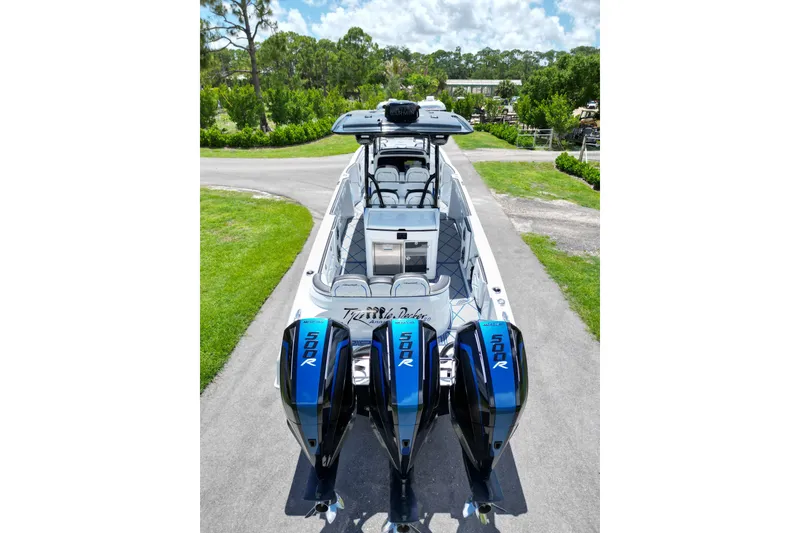 Slide: The Image of 2024 Renegade 38 Open boat with triple 500R engines, parked on a scenic driveway. - 15
