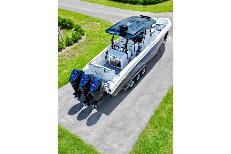 Slide: The Image of 2024 Renegade 38 Open boat with triple outboard engines, parked on a paved driveway. - 16