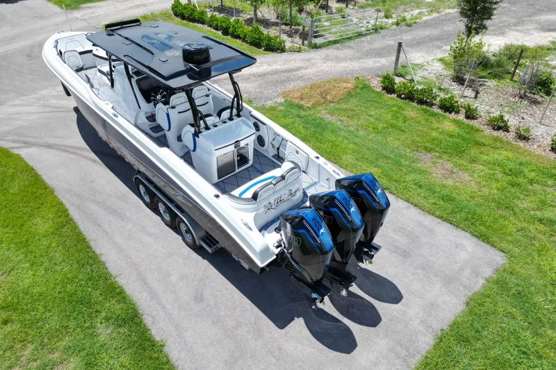 Slide: The Image of 2024 Renegade 38 Open boat with triple engines on a trailer, parked on a driveway. - 17