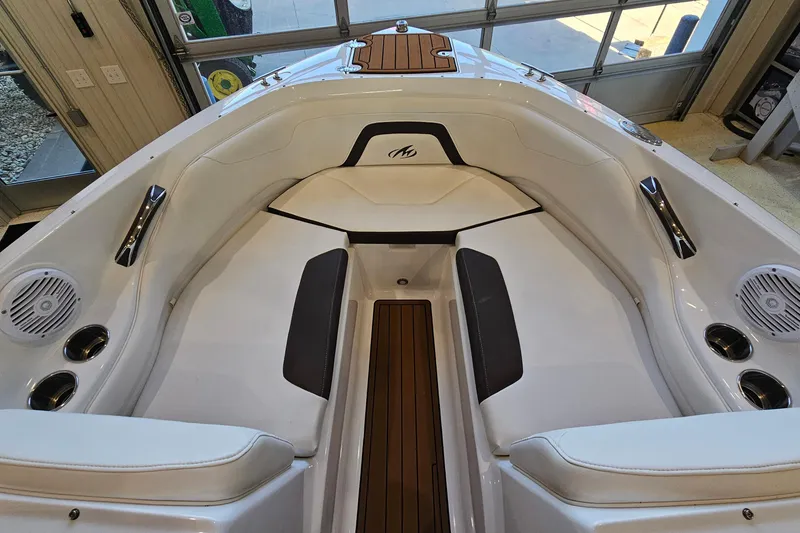 Slide: The Image of 2021 Monterey 224FS boat interior with white seating and wood accents in showroom. - 16