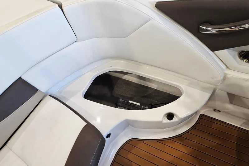 Slide: The Image of 2021 Monterey 224FS boat interior storage compartment with white and brown seating. - 24