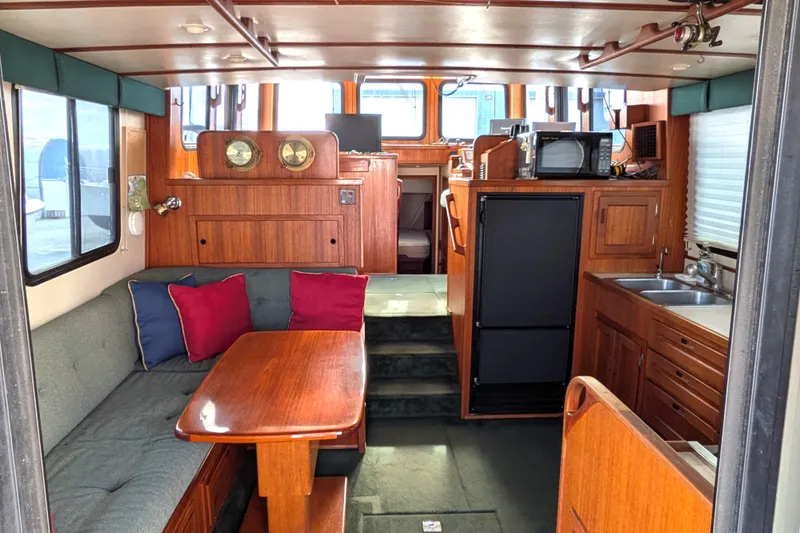 Slide: The Image of Cozy interior of 2001 Nordic Tug 37 with wooden table, cushioned seating, and nautical decor. - 16