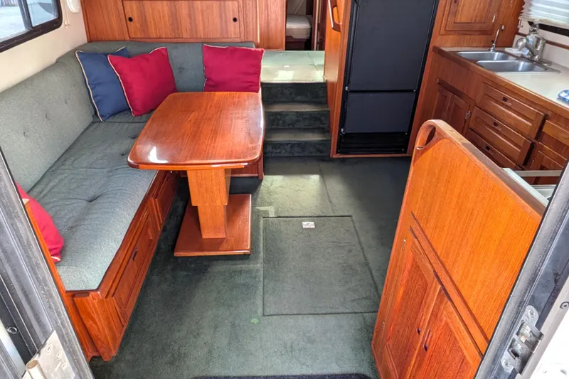 Slide: The Image of Cozy interior of a 2001 Nordic Tug 37 with wooden table and cushioned seating. - 17