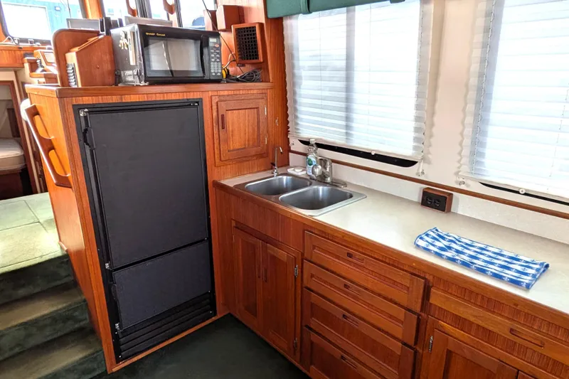 Slide: The Image of 2001 Nordic Tug 37 interior kitchen with wooden cabinetry, dual sink, and stove. - 20