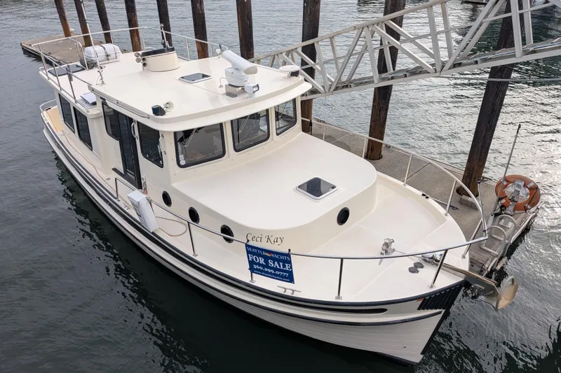 Slide: The Image of Interior of a 2001 Nordic Tug 37, featuring a cozy dining area and kitchenette. - 9