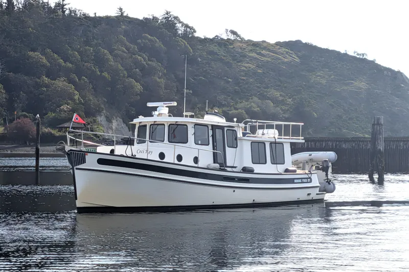 The Image of 2003 Nordic Tug 37 boat on calm water with scenic hillside background. - 0