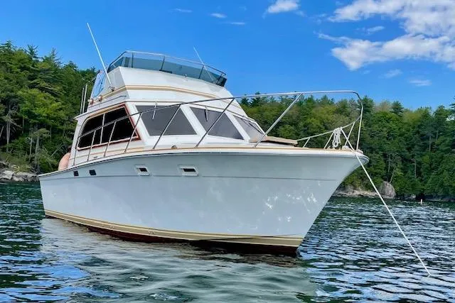 Slide: The Image of 1984 Egg Harbor 33 Convertible yacht on serene water with lush forest backdrop. - 16