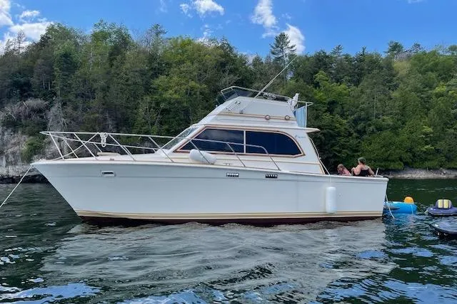 Slide: The Image of 1984 Egg Harbor 33 Convertible yacht on a serene lake with lush forest backdrop. - 18