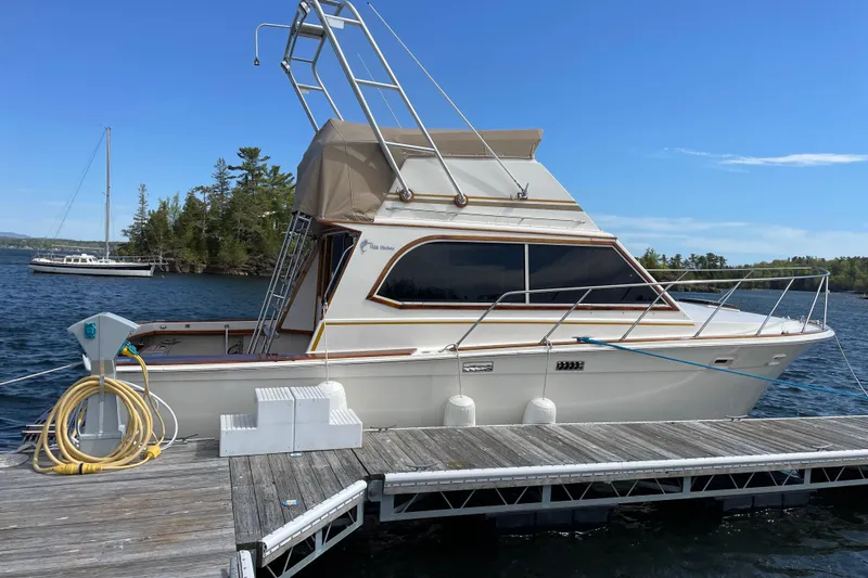 Slide: The Image of 1984 Egg Harbor 33 Convertible yacht docked on a sunny day, with scenic water and trees. - 2