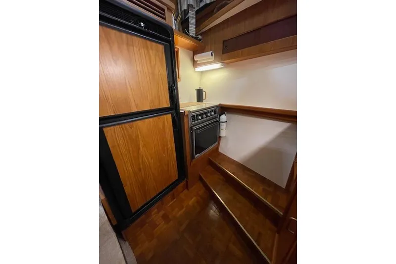 Slide: The Image of 1984 Egg Harbor 33 Convertible yacht interior kitchen with wooden cabinetry and appliances. - 30