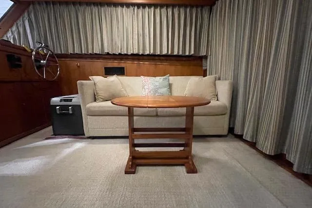 Slide: The Image of 1984 Egg Harbor 33 Convertible interior with beige sofa, wooden table, and nautical decor. - 34