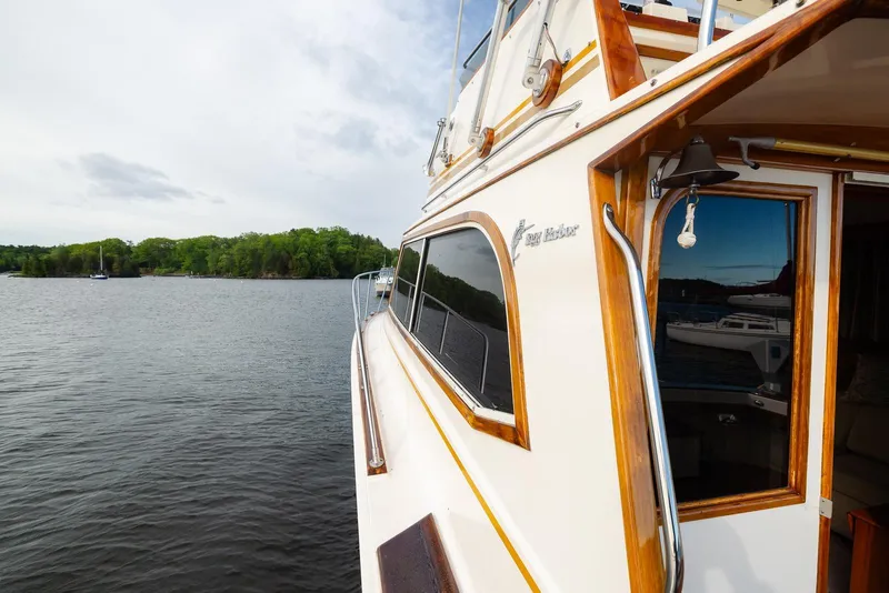 Slide: The Image of 1984 Egg Harbor 33 Convertible yacht on serene lake with lush green shoreline. - 53