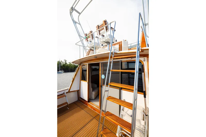 Slide: The Image of 1984 Egg Harbor 33 Convertible yacht with wooden deck and ladder, docked by the water. - 55