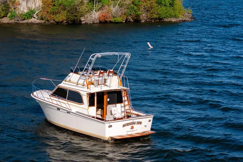 Slide: The Image of 1984 Egg Harbor 33 Convertible boat on a lake near a wooded shoreline. - 68