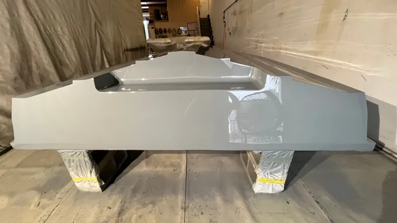 Slide: The Image of A gray boat hull rests on supports in a workshop. - 26