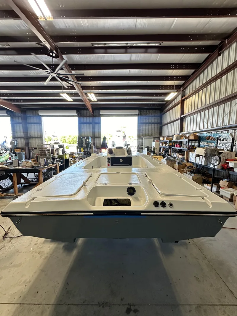 Slide: The Image of A 1997 Back Country 171 Pro Guide boat in a warehouse. It features a simple, open deck design. - 24