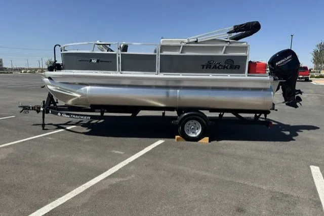 The Image of 2026 Sun Tracker Bass Buggy 16 XL Select pontoon boat on trailer in parking lot. - 0