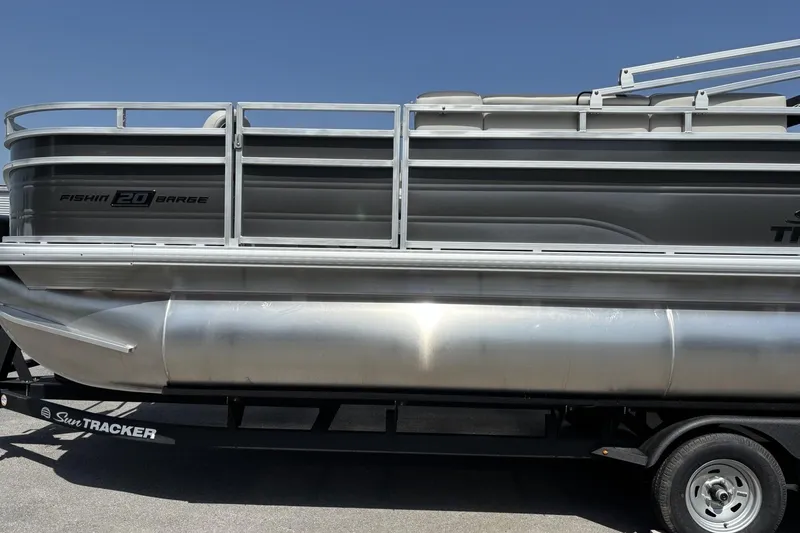 Slide: The Image of 2026 Sun Tracker Fishin' Barge 20 DLX pontoon boat on trailer, side view. - 2