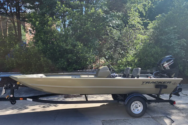 The Image of 2026 Tracker Grizzly 1754 SC boat on trailer, surrounded by lush greenery. - 0