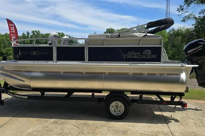 The Image of 2026 Sun Tracker Bass Buggy 16 XL Select pontoon boat on trailer, outdoors. - 0