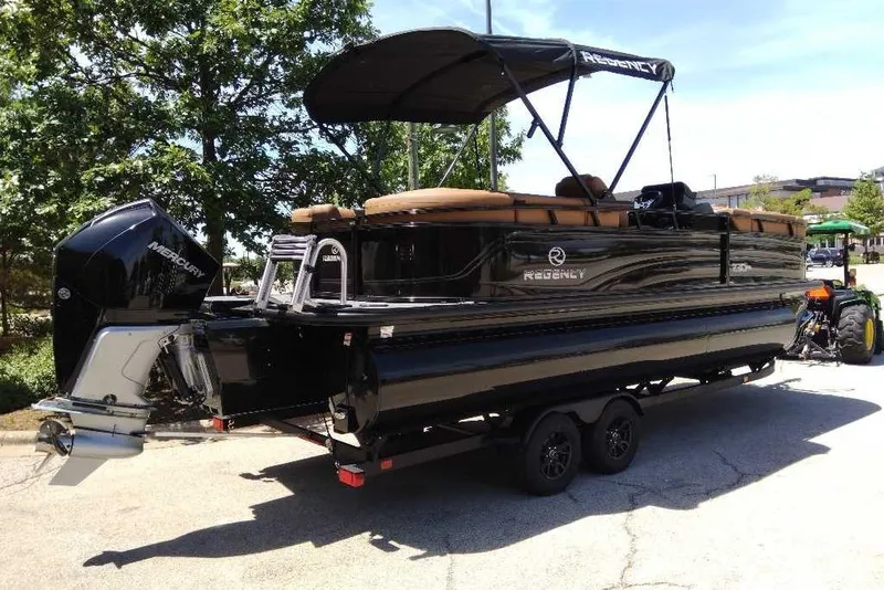 Slide: The Image of 2026 Regency 230 DL pontoon boat with Mercury engine on trailer, parked outdoors. - 63