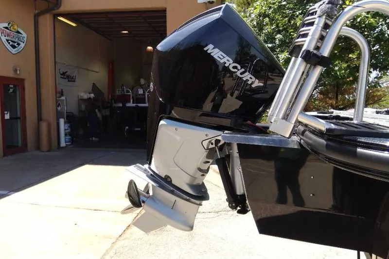 Slide: The Image of Outboard motor on a 2026 Regency 230 DL boat, parked outside a workshop. - 69