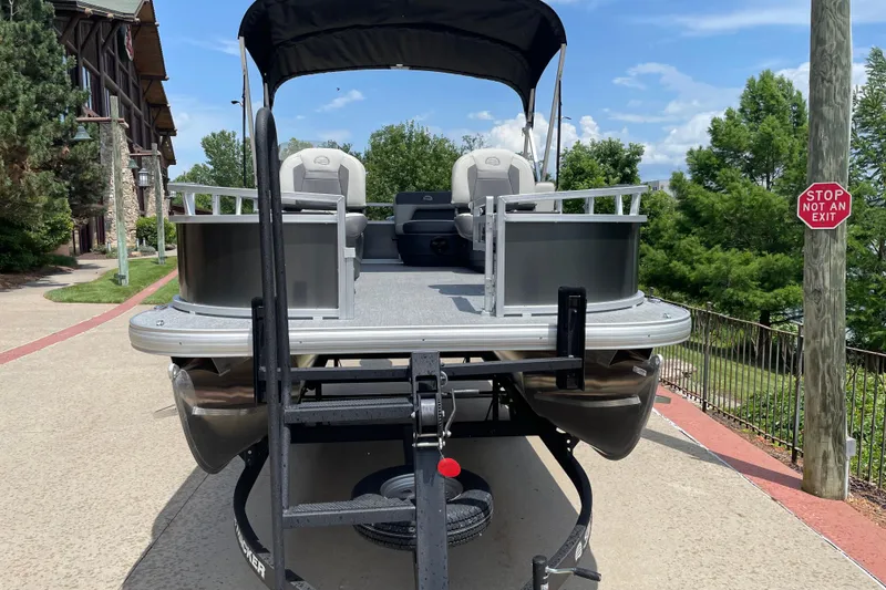 Slide: The Image of 2026 Sun Tracker Bass Buggy 16 XL Select pontoon boat on trailer, parked outdoors. - 1