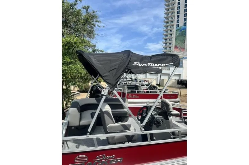 Slide: The Image of 2026 Sun Tracker Bass Buggy 16 XL Select pontoon boat with canopy, parked outdoors. - 11