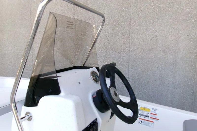 Slide: The Image of Steering console of 2026 Mako Pro Skiff 15 CC with windshield and controls. - 12