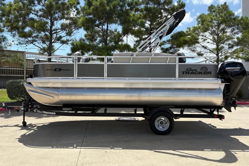 The Image of 2026 Sun Tracker Bass Buggy 18 DLX pontoon boat on trailer, parked outdoors. - 0