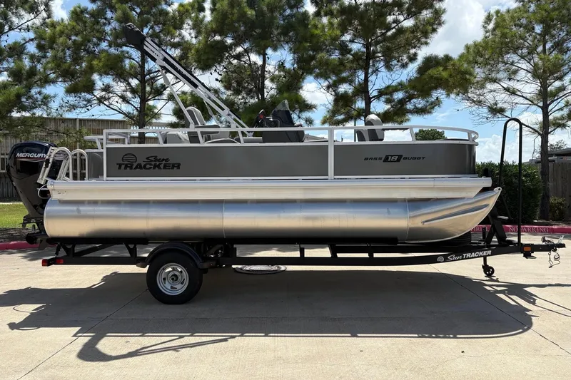 Slide: The Image of 2026 Sun Tracker Bass Buggy 18 DLX pontoon boat on trailer, parked outdoors. - 3