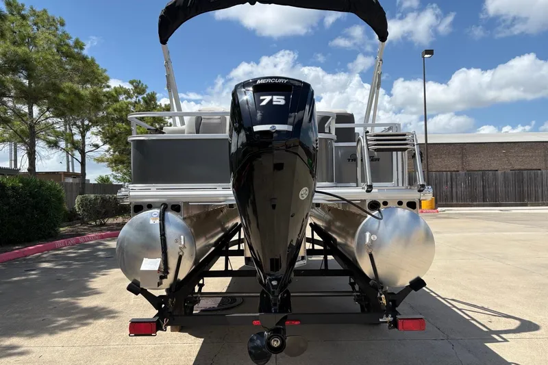 Slide: The Image of 2026 Sun Tracker Bass Buggy 18 DLX pontoon boat with Mercury 75 engine, parked outdoors. - 6