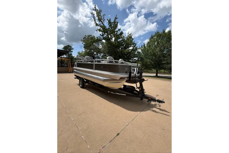 The Image of 2026 Sun Tracker Party Barge 18 DLX pontoon boat on trailer, parked outdoors. - 0