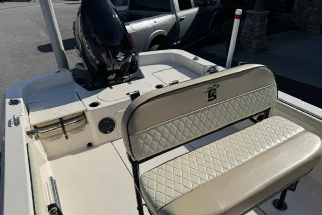 Slide: The Image of 2022 Carolina Skiff 23 LS boat interior with cushioned seating and motor, parked outdoors. - 9