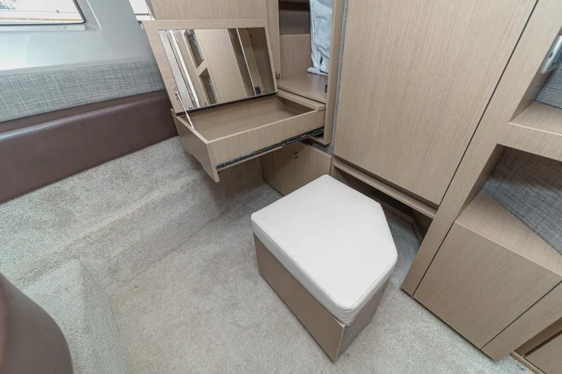 Slide: The Image of 2017 Sea Ray Sundancer 400 cabin interior with vanity, mirror, and cushioned stool. - 33