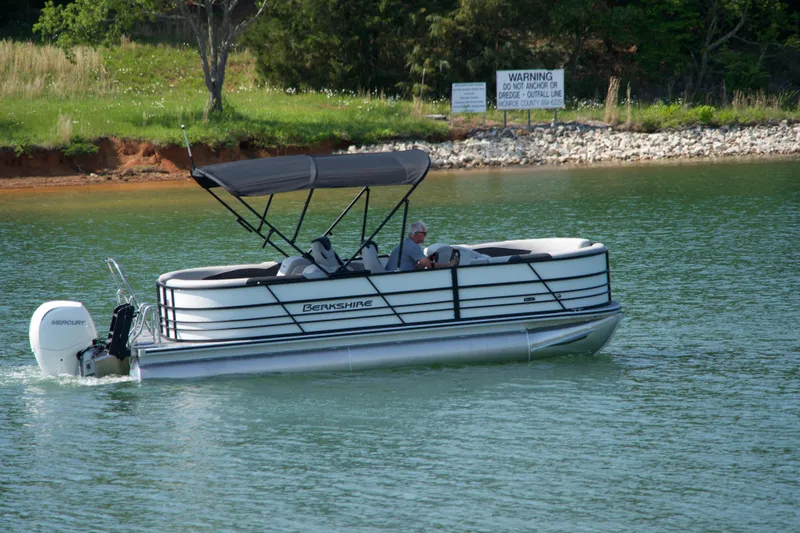 Slide: The Image of 2026 Berkshire 22 RFX LE pontoon boat cruising on a serene lake. - 2