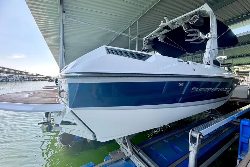 Slide: The Image of 2022 Nautique Super Air Nautique GS24 boat docked under a covered marina. - 23