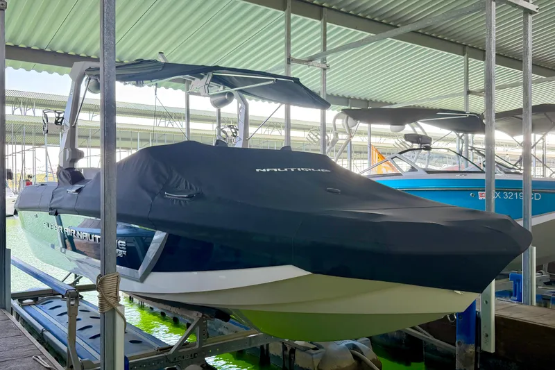 Slide: The Image of 2022 Nautique Super Air Nautique GS24 boat covered and docked in a marina. - 24