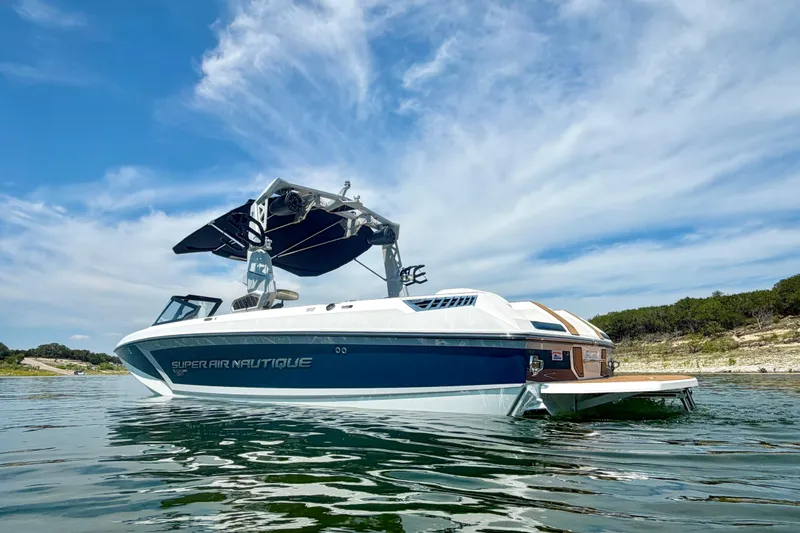 Slide: The Image of 2022 Nautique Super Air Nautique GS24 boat on calm water under a blue sky. - 4