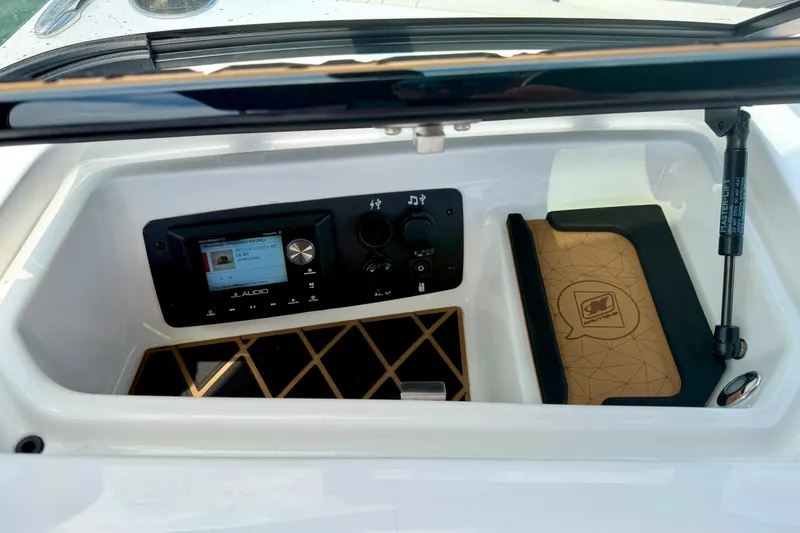 Slide: The Image of 2022 Nautique Super Air Nautique GS24 dashboard with JL Audio system and storage compartment. - 43